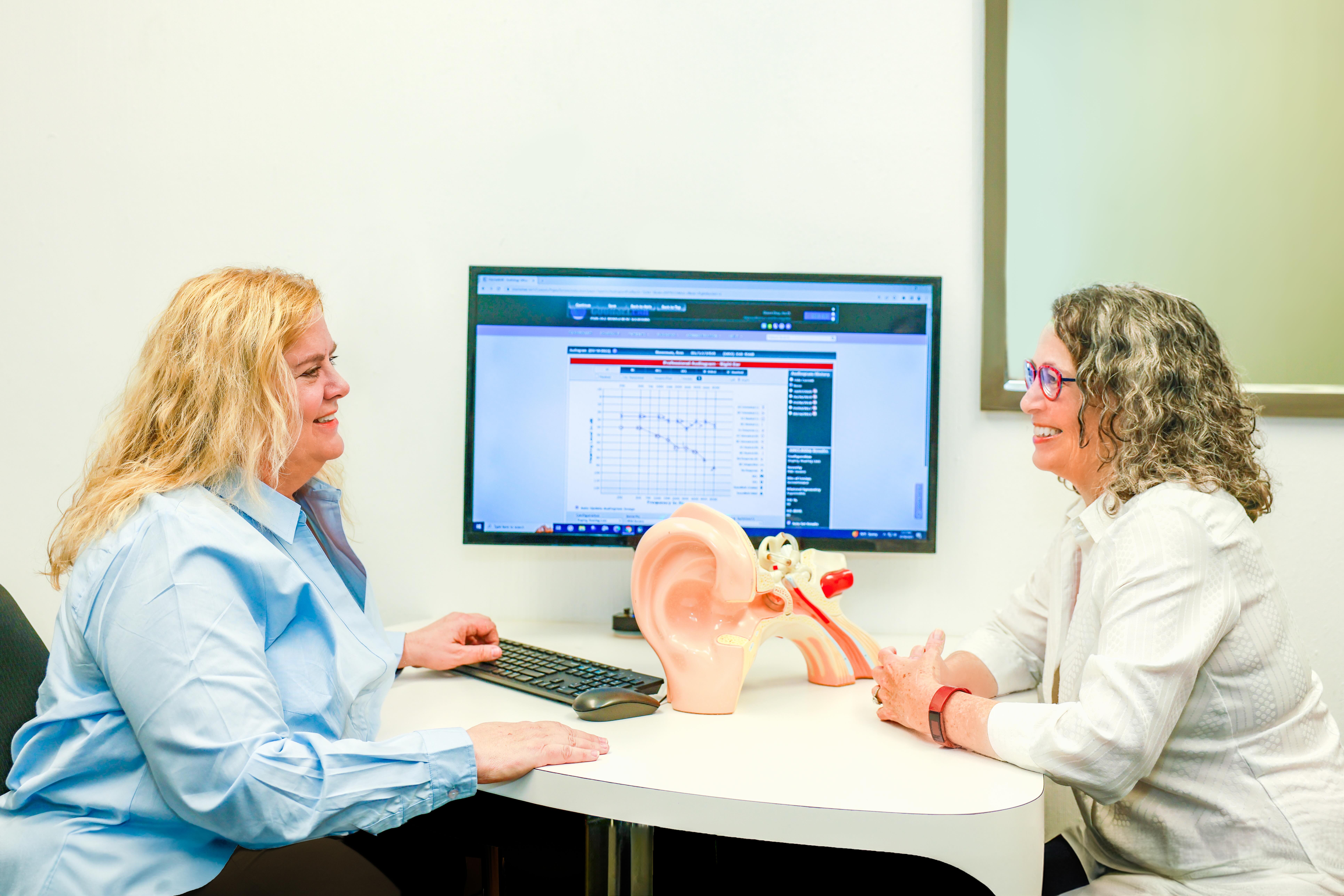 Two audiologists smiling at each other